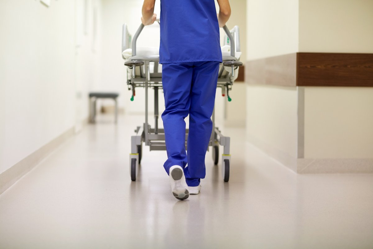 helsepersonell i blått triller en sykehusseng