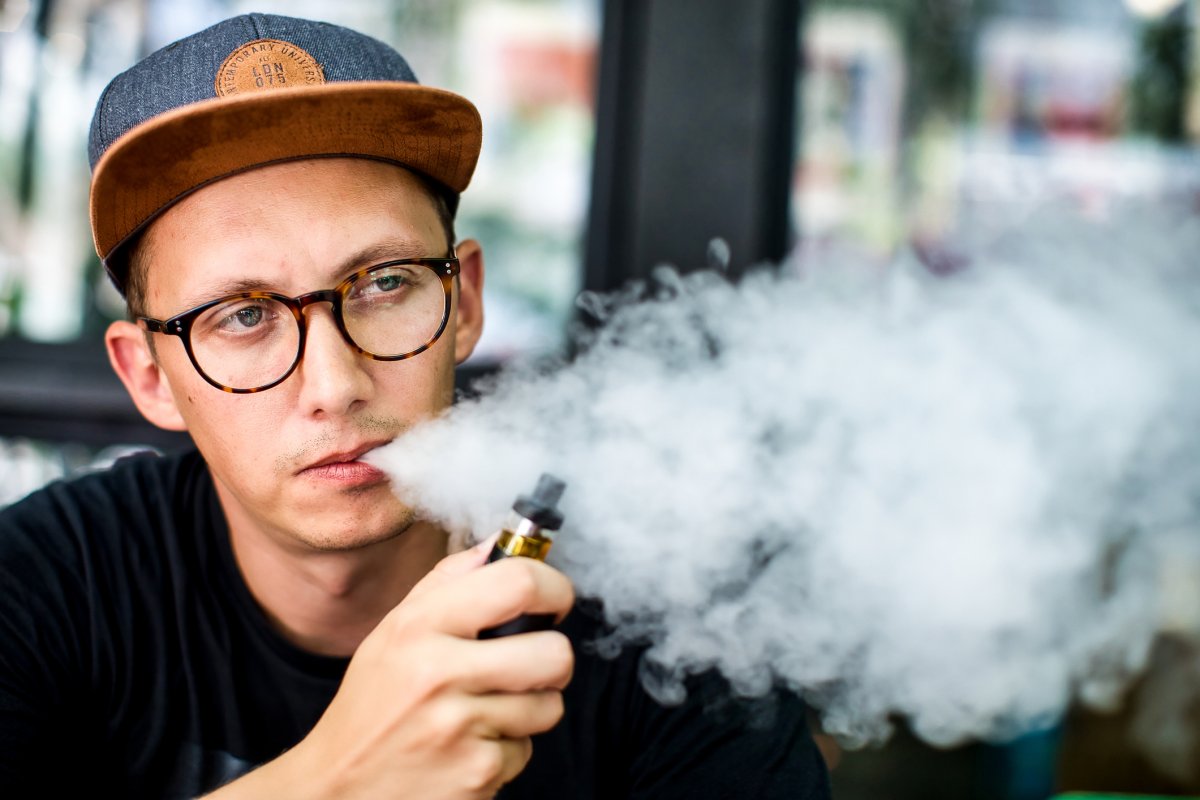 Ung mann blåser ut røyk (vape)